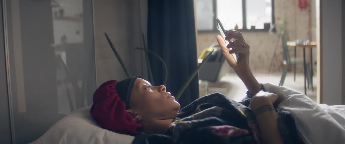 Woman laying in bead looking at her phone in the bedroom at home