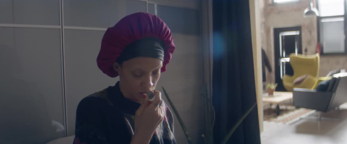 A woman taking her temperature by mouth while sitting in bed