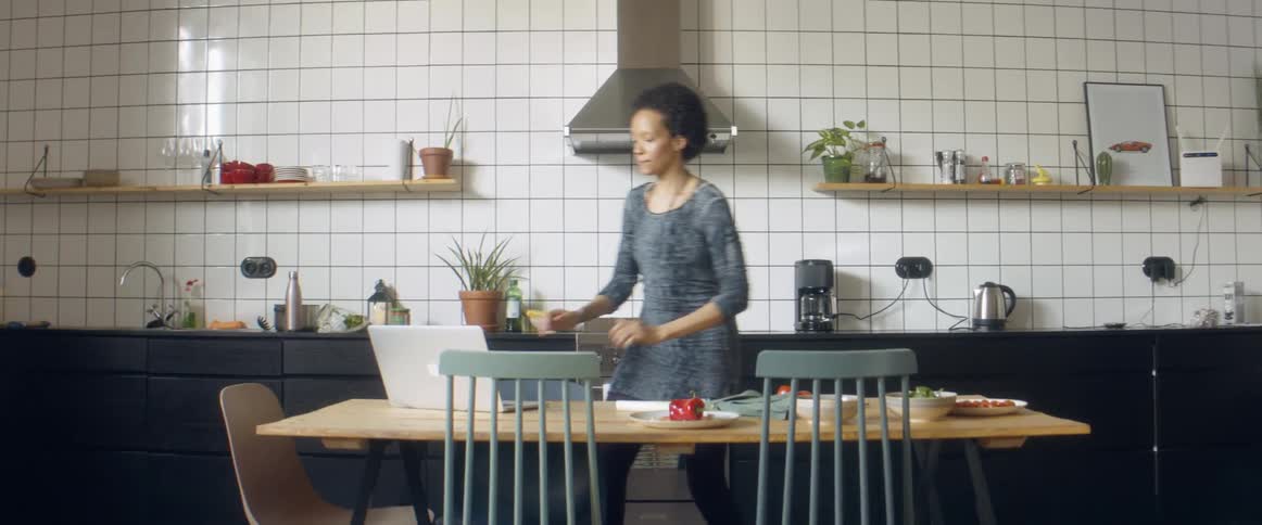 Woman dances while preparing food in the kitchen at home