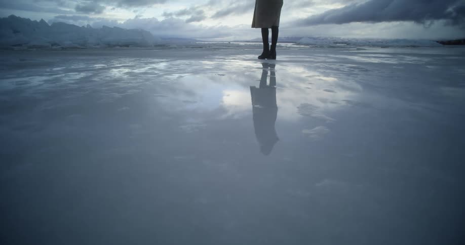 A person is pacing on wet sand, frozen water, reflection
