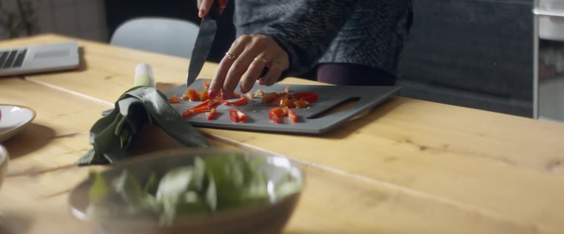A black female chopping vegetables in the kitchen