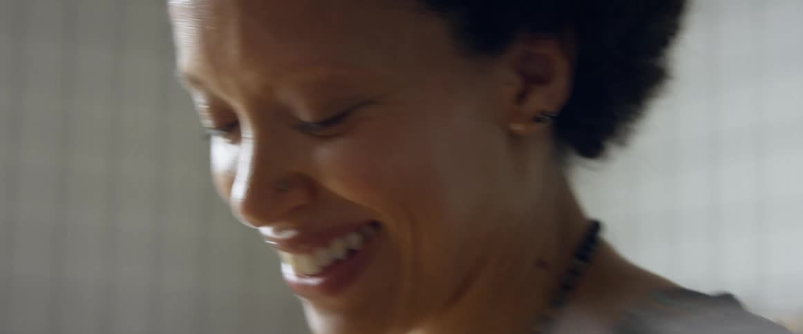 A woman smiling and laughing while dancing near a sunny window