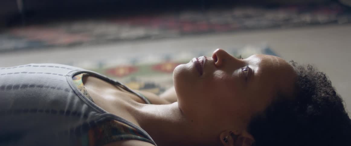 Woman with a grey top lies down on the floor and relaxes after workout in the living room at home