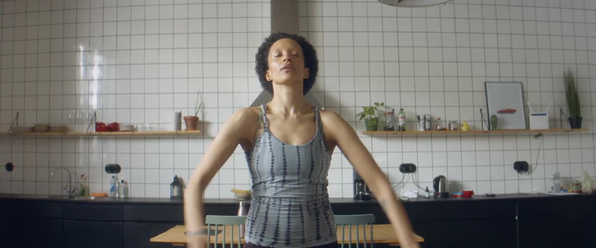 A woman stands in her kitchen stretching her arms