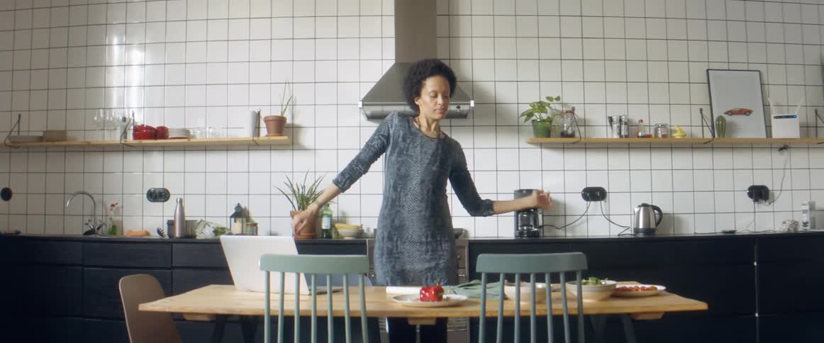 A woman cooking in a kitchen at home dances around playfully