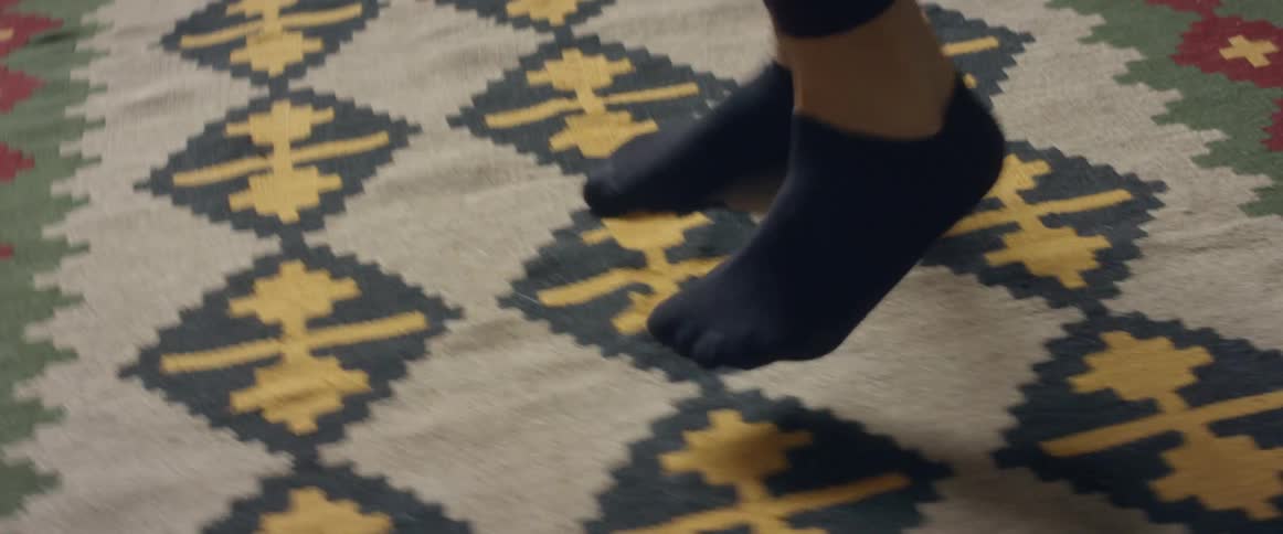 Close up of the foot of a woman working out over the rug in the living room