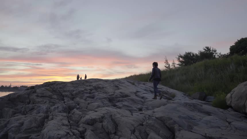 A woman hikes towards other people near the shore