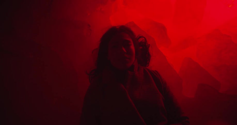 Woman looking at the camera lays on the floor reflecting red light