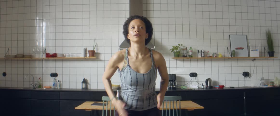 A woman runs in place for exercise while in the kitchen of a house during the day