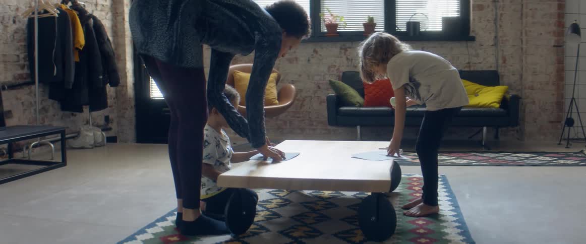 A woman and two boys in a room next to a table with wheels