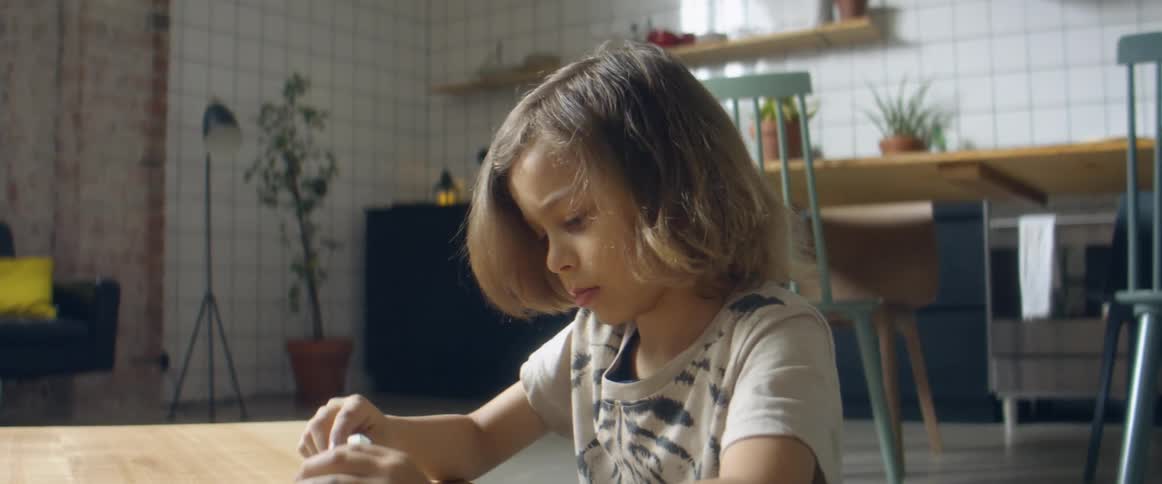 Boy carving while playing over a table in the living room at home