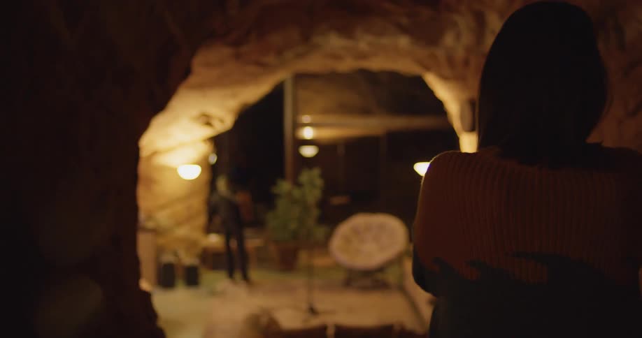 A woman watching a man play an acoustic guitar indoors