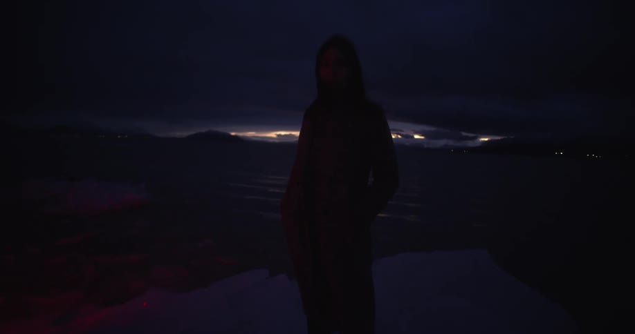 A woman stands outside as a red light flashes on her
