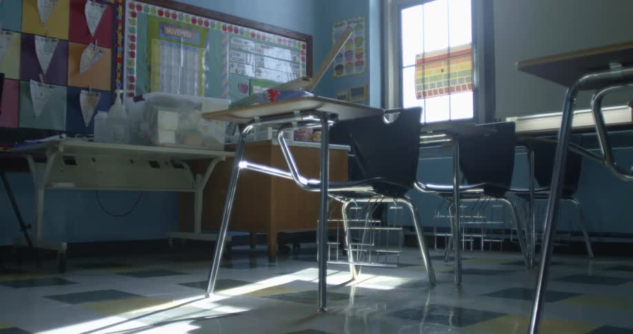 A classroom with chairs and desks with a wall and window in the background