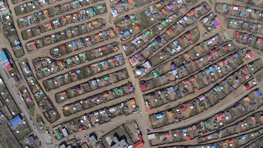 Traffic flows along streets between colorfully roofed houses