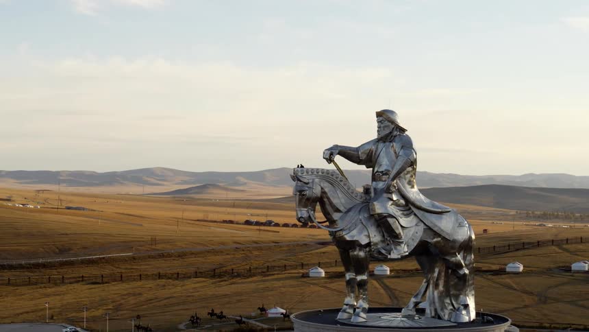 A building with a statue on top with a landscape the sky and clouds in the background