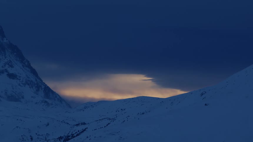 Clouds move over snow covered hills