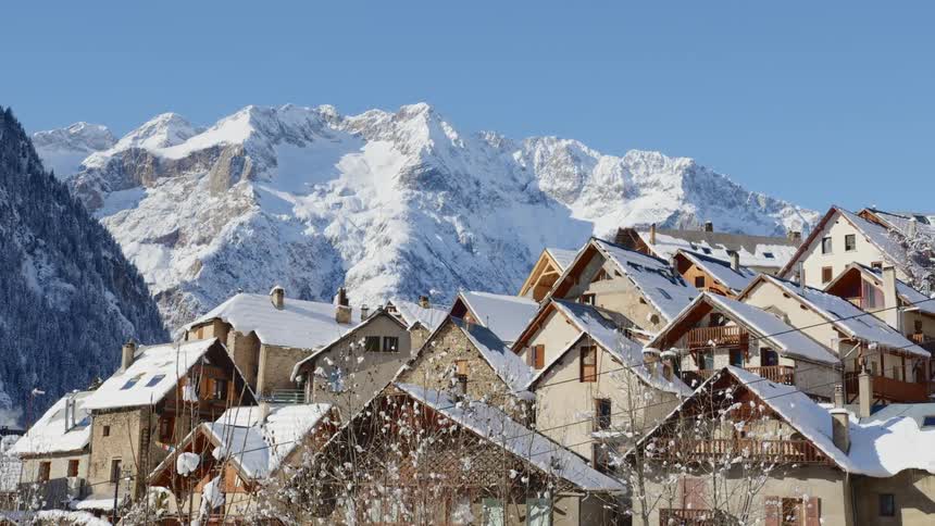 Town with snow covered roofs nestles against mountains