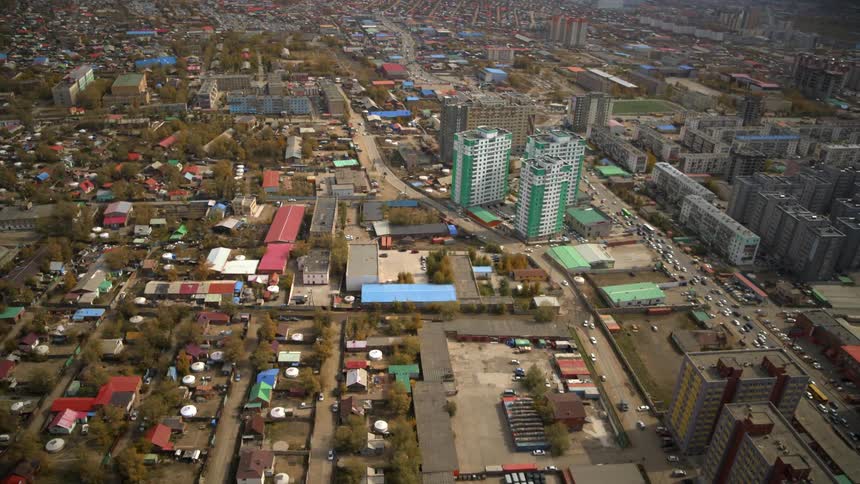 A downtown city is surrounded by dense neighborhoods near a mountain range