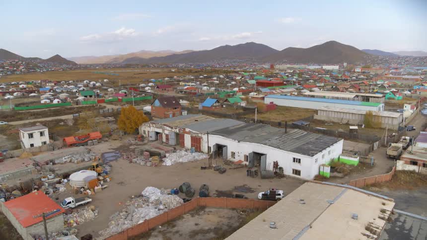 A town with buildings with a mountain range the sky and clouds in the background