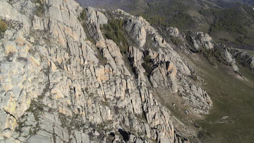 Shadow covers deep crevices of mountains covered partly in forest