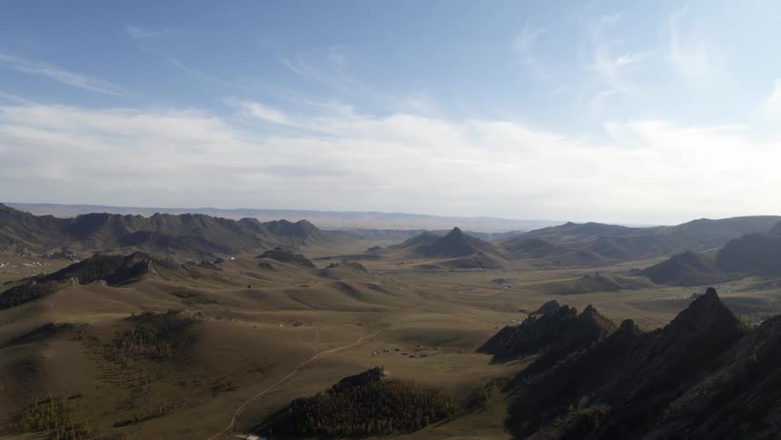 A landscape with hills with a mountain range the sky and clouds in the background