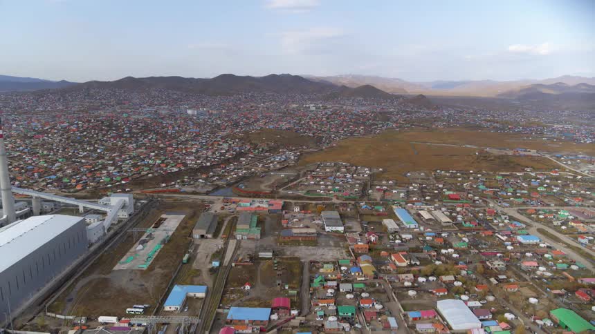 A town with roads and buildings with a mountain range the sky and clouds in the background