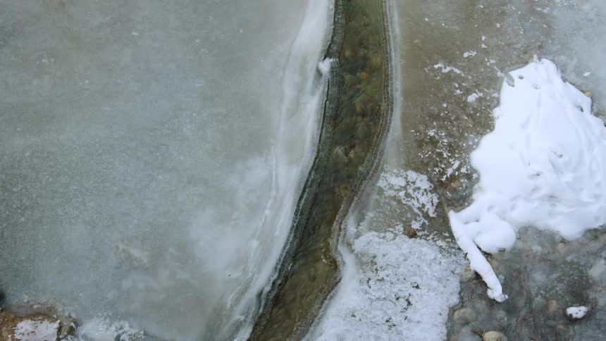 A small stream runs through an ice covered field