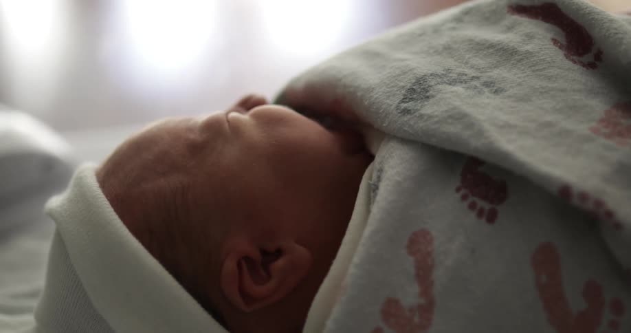 A newborn baby lies swaddled in a blanket