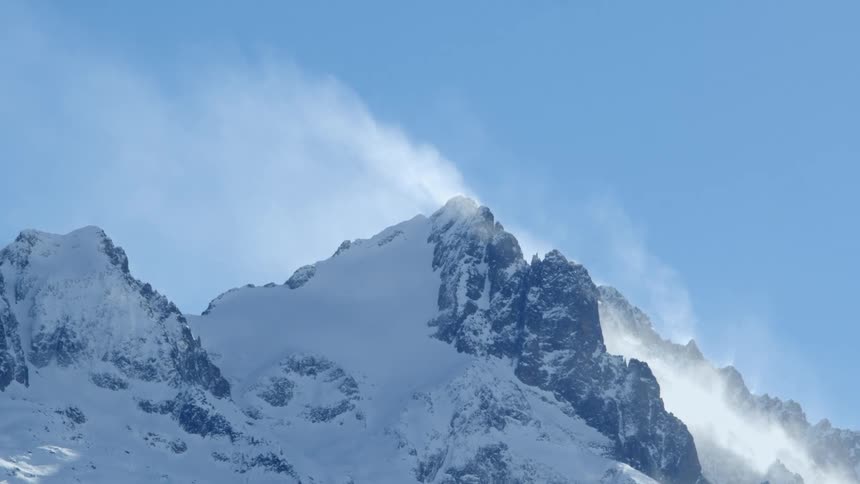 Wind blowing over a snowy mountain range on a winter day