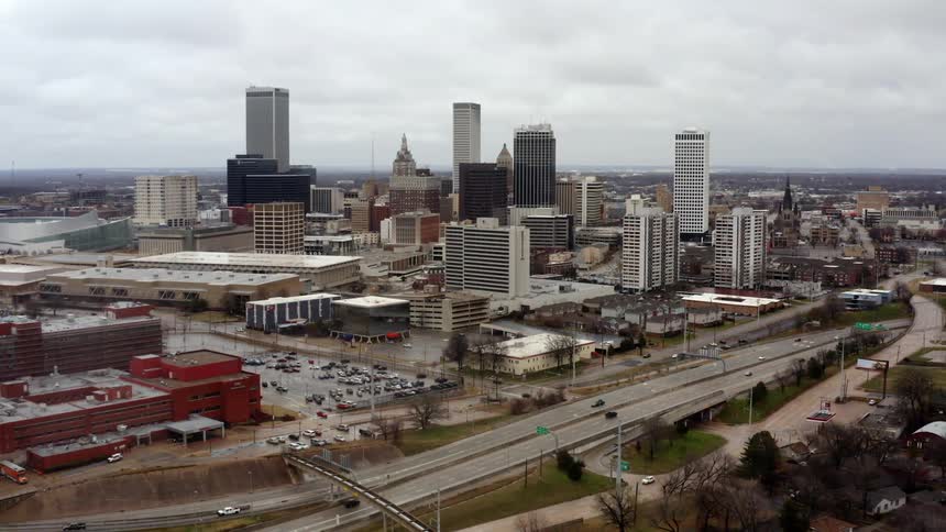 Traffic flows along freeway past downtown skyscrapers under overcast sky