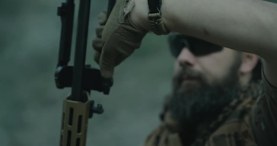 A man with gloves a hat and sunglasses holding a rifle