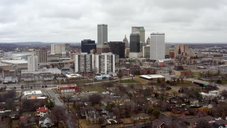 A city with buildings and trees with the sky and clouds in the background