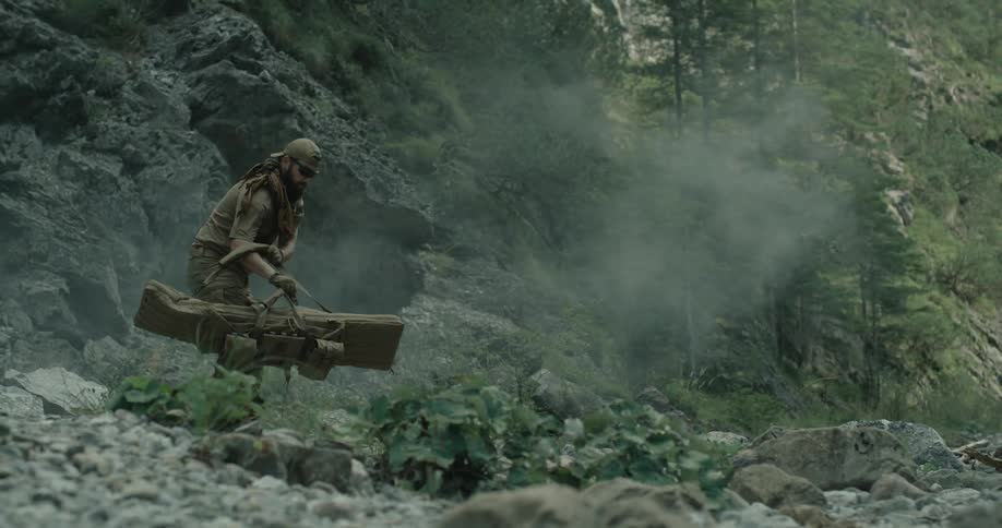 A man with a large bag standing in a forest