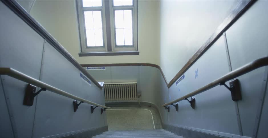 Stairs lead downward toward radiator sitting on wall under window