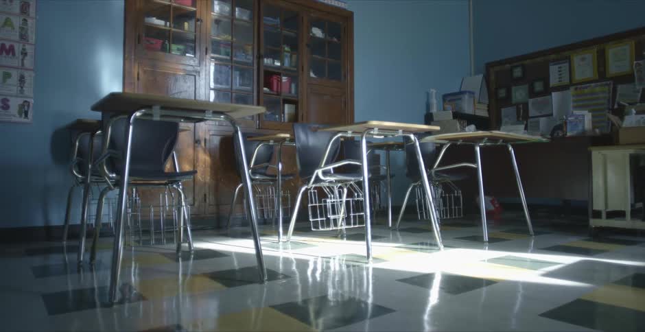 There is a classroom full of empty desks and sunlight pouring in