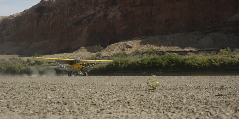 A small yellow airplane lands in the desert