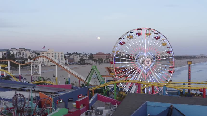 Ferris wheel in an amusement park on the shoreline of a beach next to a city