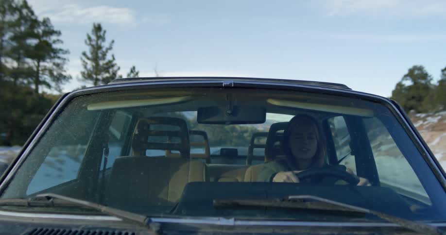 A woman is driving a car on a road in winter