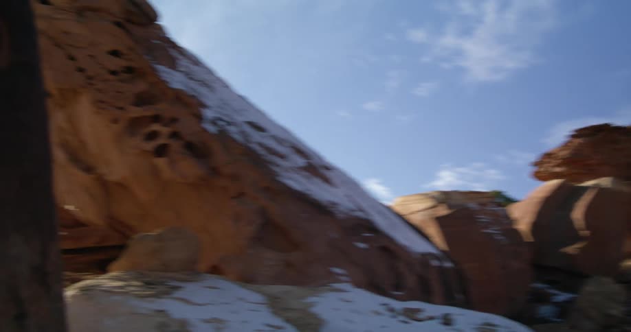 In a rocky and mountainous landscape a single prominent rock protrusion is coated in snow