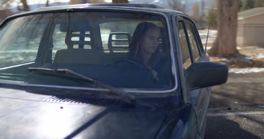 A young woman driving a car does a u turn on a road during the day
