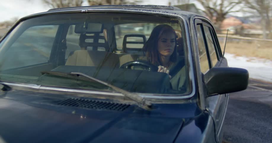 A woman is driving a car on a road in winter
