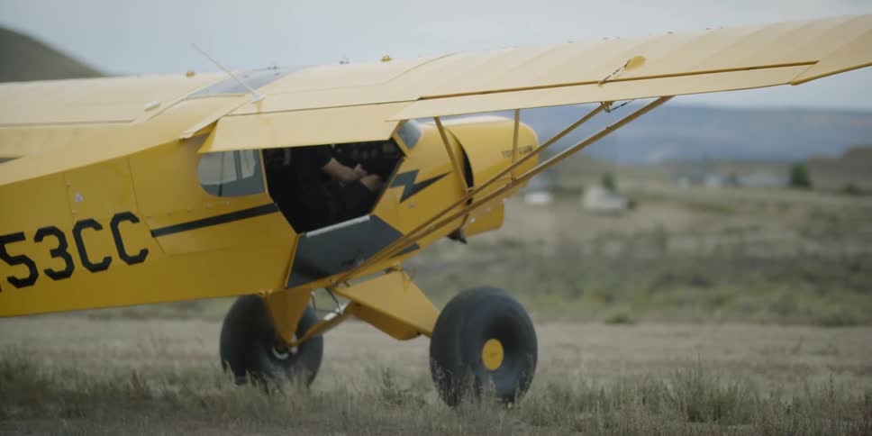 A yellow plane rolls forward across a field