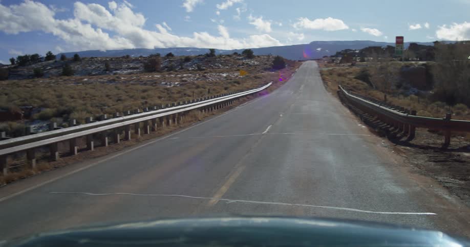 A car traveling on a small town road on a sunny day