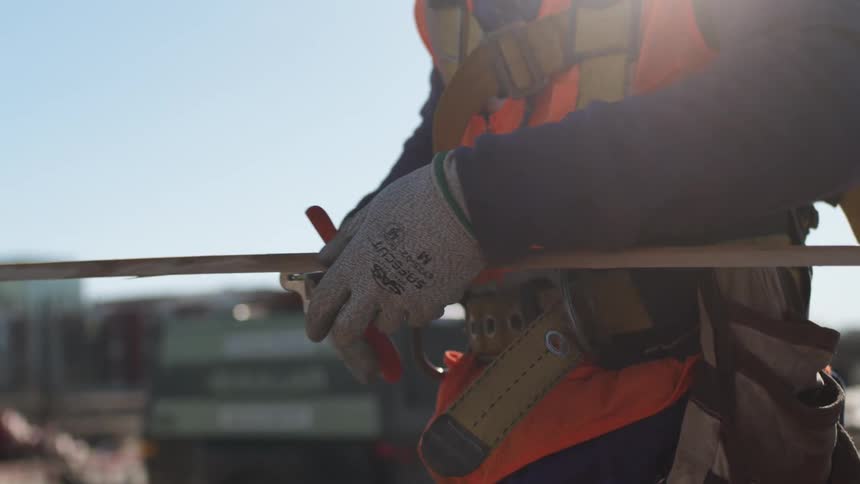 Construction worker uses a cutting tool on a metal pipe on a construction site
