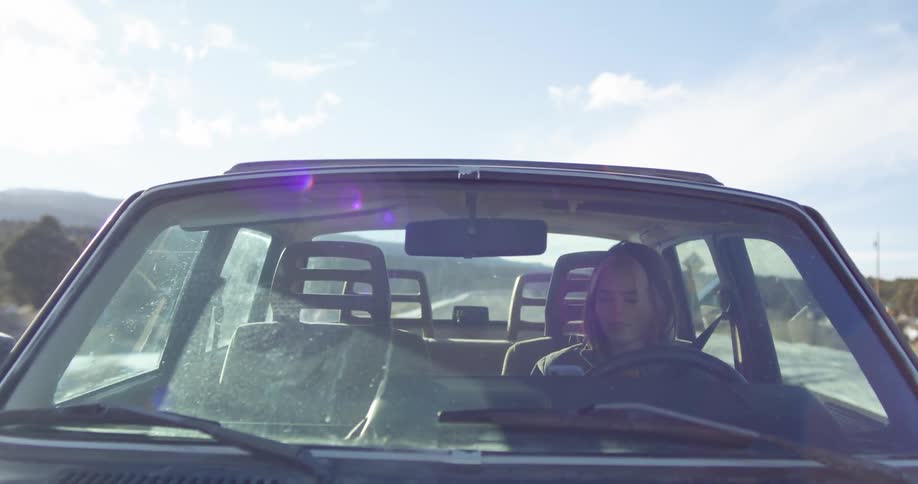 A woman talking on a phone while driving on a rural road