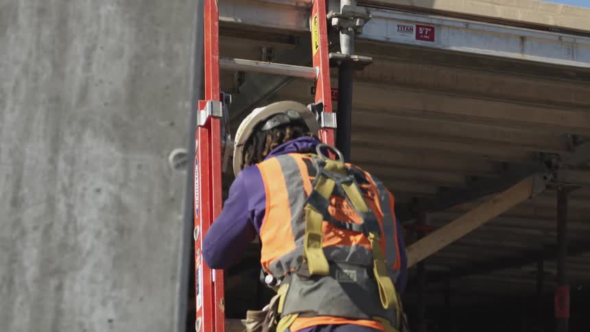 An employee climbing down a ladder at a construction site
