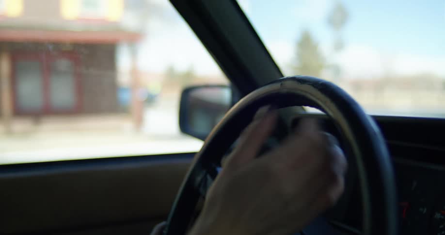 A woman drives a vehicle through a town during the day