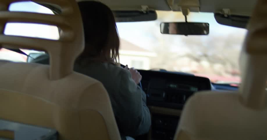 A woman steers to the right and left as she drives out of a parking lot