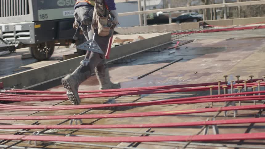 A person with boots and a utility belt walking on a construction site